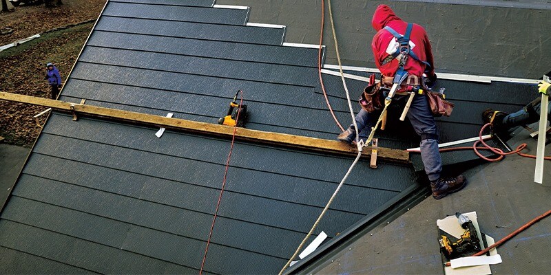 Certified GAF roofing contractor installing a metal roof shingle on a home